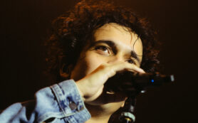 Copertina di “Serve fare schifo ogni tanto. Se a Sanremo avessi cantato intonato non saremmo qui”: Tananai ironizza e si commuove al Forum di Milano sold out. Lo show di formazione e della maturità