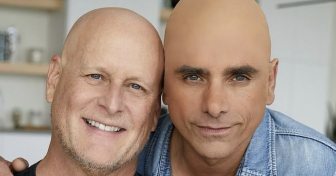 Copertina di “Non è così che si sostiene chi è malato di cancro”: polemiche contro John Stamos per aver indossato una calotta calva con il collega Dave Coulier