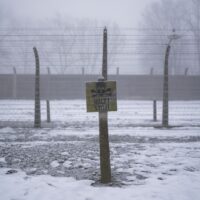 A wooden sign with the word STOP stands in front of what was an electric barbed wire fence inside the former Nazi German extermination and labor camp Auschwitz I, in Oswiecim, Poland, Thursday, Jan. 23. 2025. (AP Photo/Oded Balilty)