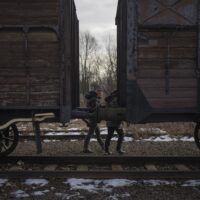 People visit railroad tracks and a carriage used for prisoner transports in WWII, just outside the former Nazi German concentration and extermination camp Auschwitz-Birkenau in Oswiecim, Poland, Saturday, Jan. 25. 2025. (AP Photo/Oded Balilty)