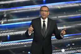 Copertina di Accendi la televisione, vedi Carlo Conti e il tempo si annulla: siamo nel 2005? O nel 2032? Tra Tra Taylor Swift e l’amico di famiglia, al via il quinto Sanremo dell”era contiana’
