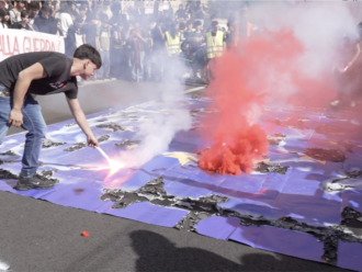 Copertina di Corteo contro i tagli all’istruzione, studenti bruciano una maxi bandiera dell’Europa davanti al ministero
