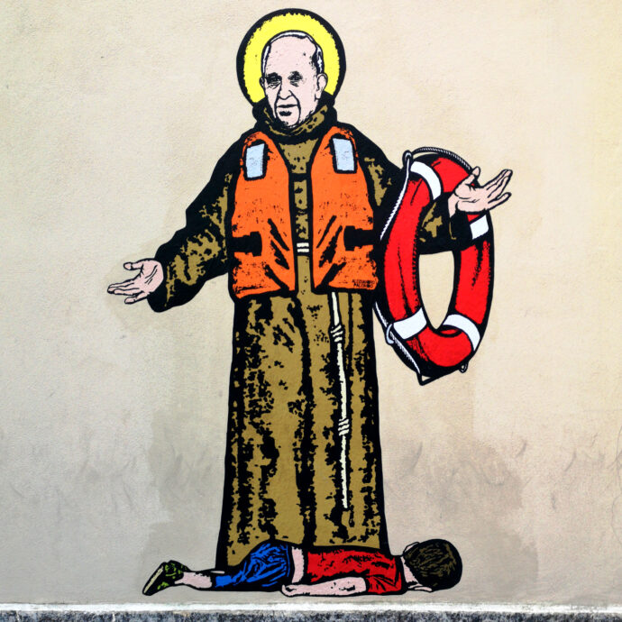 Papa Francesco con il giubbotto salvagente e il piccolo Alan Kurdi ai suoi piedi: il murale apparso sui muri della Caritas a Milano