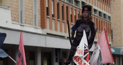 Copertina di Dl Sicurezza, gli studenti vestono Meloni da fascista fuori dall’assemblea di Confindustria a Bologna: “Tempi bui”
