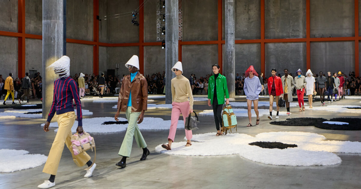 Dai tappeti floreali di Prada al blu pantesco di Armani: a Milano la moda uomo resiste alla guerra e racconta un mondo sospeso tra sogno e crisi