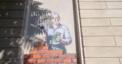 Copertina di Sala erige un muro di mattoni col simbolo del dollaro: l’opera sulla facciata della Galleria d’Arte Moderna