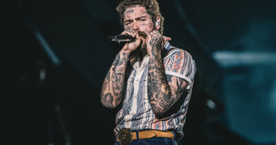 Copertina di “Non c’è nessuno in tutto l’universo che possa dirvi un c***o”: Post Malone dà la carica ai 25mila fan italiani a Milano. Ad applaudirlo anche Olly e Naska