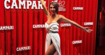 Copertina di Le rubano l’abito in treno, sfila a Venezia indossando il lenzuolo dell’hotel: “Ho dato sfogo alla mia creatività”