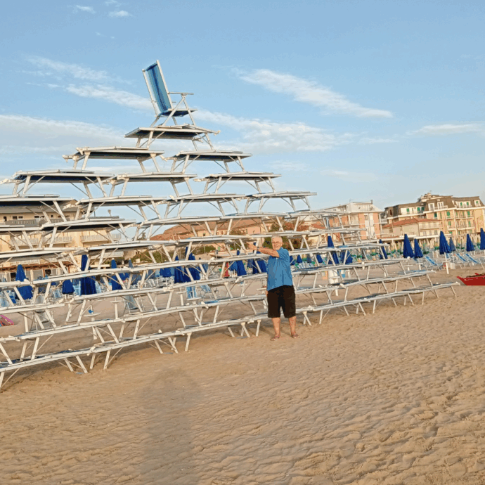 Torna la piramide di lettini in spiaggia: 56 in tutto, impilati con cura su 10 piani, sormontati da una sdraio