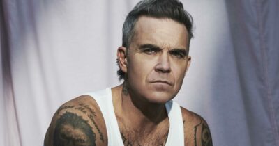 Copertina di “Il mio disco slitta sempre perché Taylor Swift pubblicherà le versioni deluxe. La settimana dopo? Potrebbero esserci gli Oasis”: Robbie Williams si sfoga