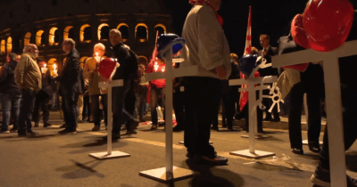 Copertina di Crollo Torre dei Conti, fiaccolata per l’operaio morto con croci bianche e caschetti da cantiere: “La strage deve finire”