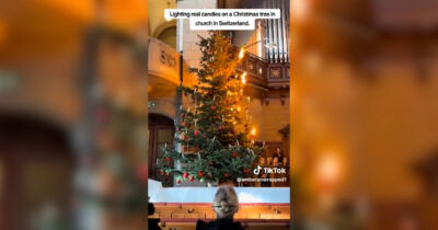 Copertina di L’abete sembra prendere fuoco, poi la magia: la surreale accensione delle candele sull’albero di Natale – Video