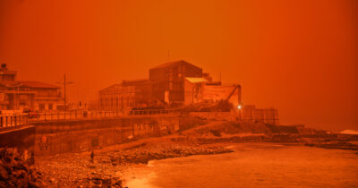Copertina di “State a casa, non uscite e serrate bene porte e finestre. Ci sono rischi per la salute”: il cielo di Creta si tinge di arancione per una potente tempesta di sabbia del Sahara e le autorità lanciano l’allarme