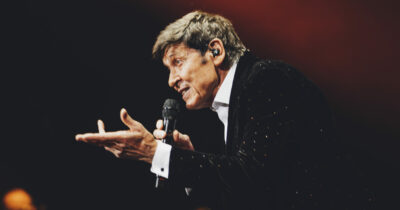 Copertina di Gianni Morandi: “Mi piacerebbe andarmene come Aznavour, il giorno prima di un concerto. Ho 81 anni, faccio 7-8 giri di pista minimo al giorno, vado in palestra. Così mi preparo per il tour”