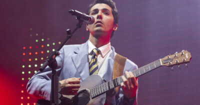 Copertina di Fulminacci a Milano è una mosca bianca elegante: nessun ospite al concerto, giacca e cravatta, grafiche minimal Anni 90, tanta musica suonata e l’amore per “le premure, le seccature, la parola schiscetta e le fatture”