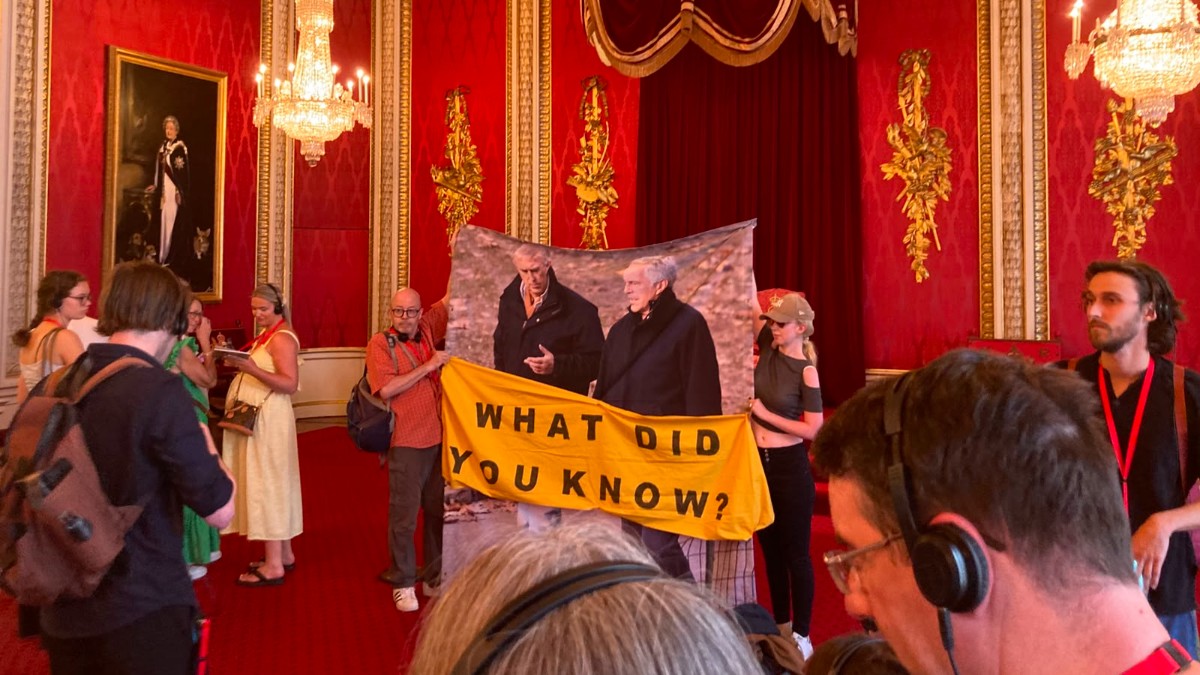 “Cosa sapevano Carlo e William? La monarchia sopravvive grazie alla segretezza”: un lenzuolo con la foto di Andrea ed Epstein nella sala del trono a Buckingham Palace