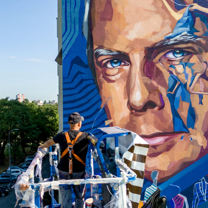 Piacenza omaggia Giorgio Armani con un murale di 27 metri: “Così la sua storia potrà ispirare i giovani come ha ispirato il mondo”. Ma l’opera dello street artist Kotè divide