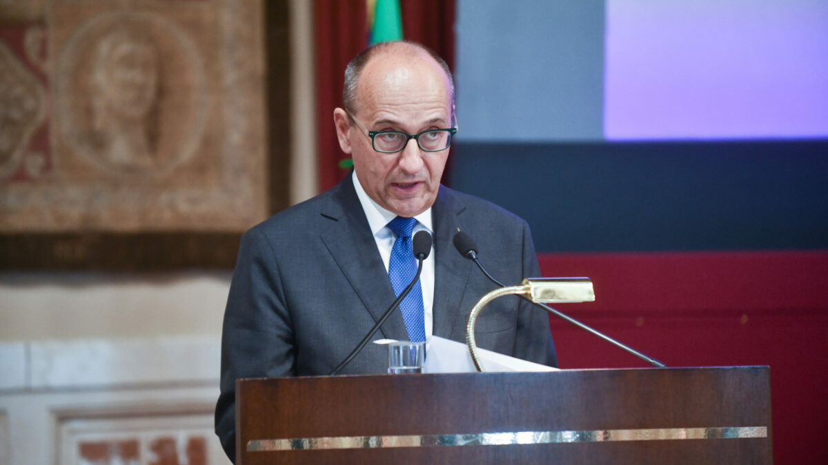 Un uomo in completo si presenta a un ufficio governativo, mentre un documento ufficiale è posato accanto a lui